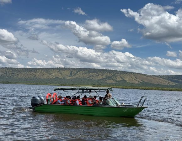 A green boat on a lake with people wearing orange jackets
