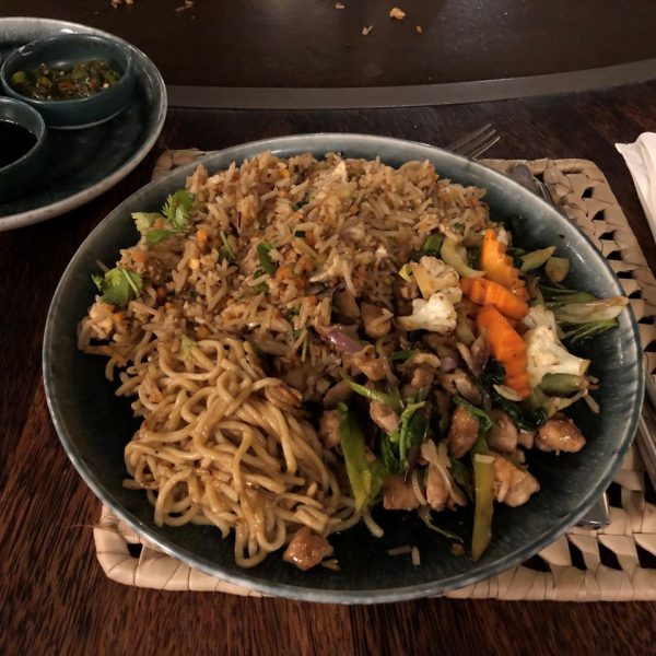 Noodles and vegetable on a plate with a side of sauces