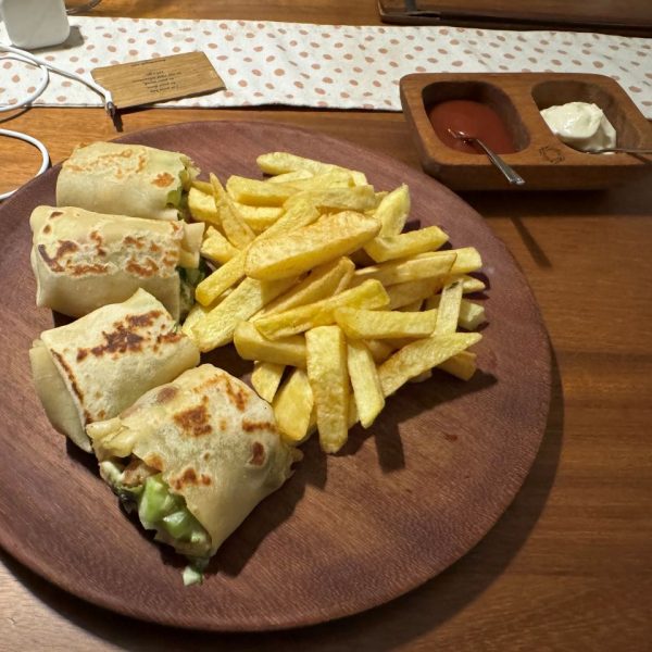 A sandwich wrap with french fries on a wooden plate