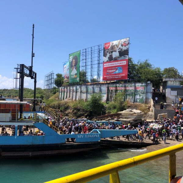 People boarding a blue ferry on a sunny day