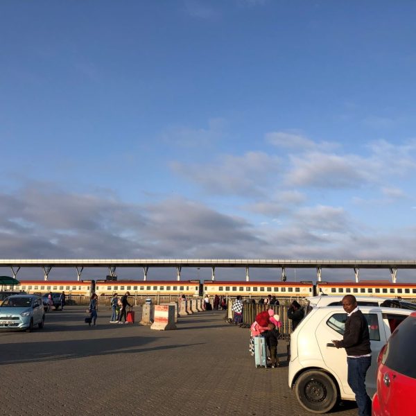 People and cars in a train station parking lot 