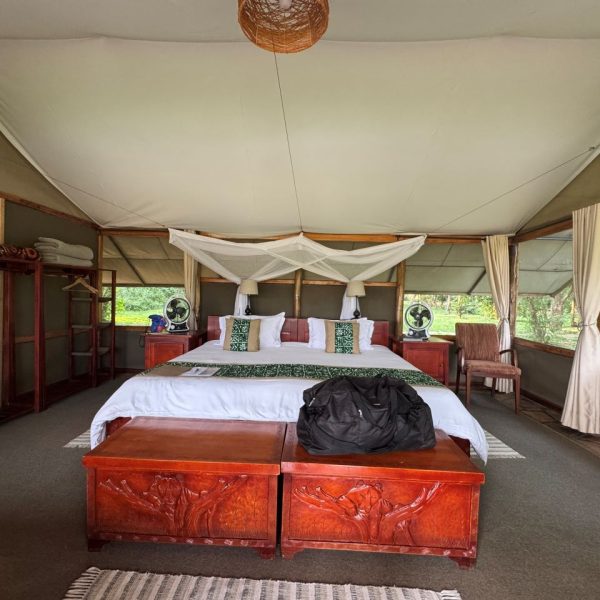 A safari tent with a bed and  mosquito net over the bed