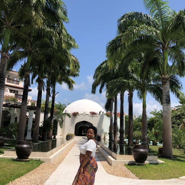 A woman posing for a photo in front of a white building 
