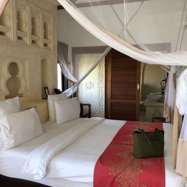 Large bed with white bed sheets and a red bed runner 