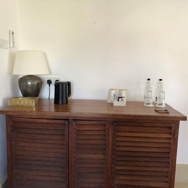 Wooden cupboard with glass bottles and a kettle on top 