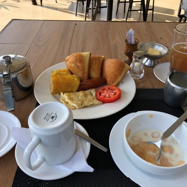 A breakfast table with cereal, tea and eggs on a plate